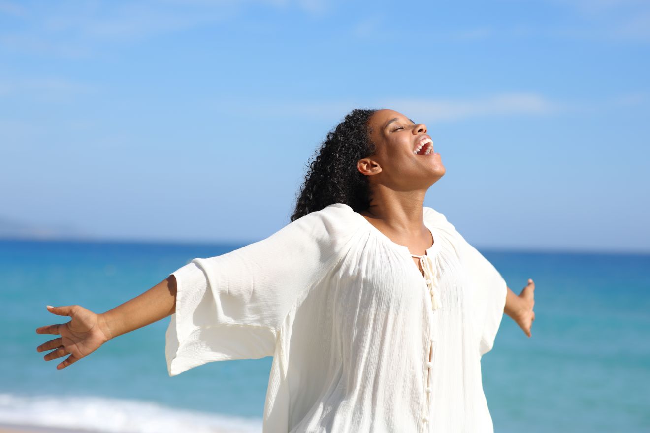 Man Experiencing Dizzy Spell woman celebrating on beach after dizziness treatment.