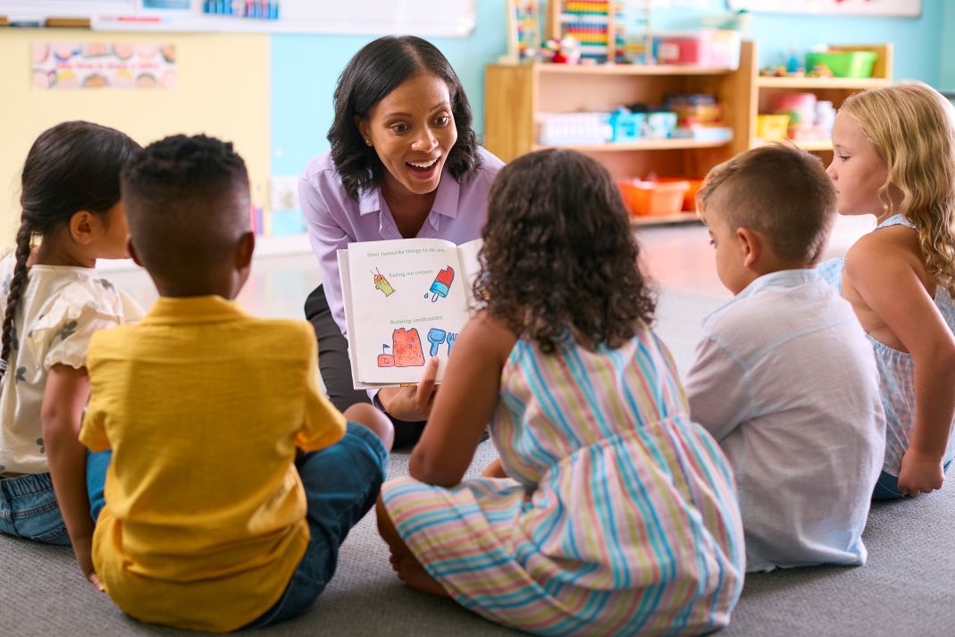 speech-delay-symptoms Children in a group reading a book together with a speech therapist